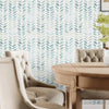A close-up view of a room featuring a green and white leaf pattern wallpaper on the wall and light upholstered chairs.