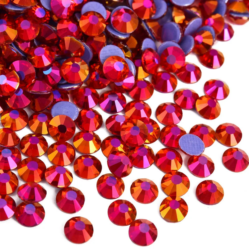 A close-up view of various red, orange, and purple faceted rhinestones scattered on a white background.