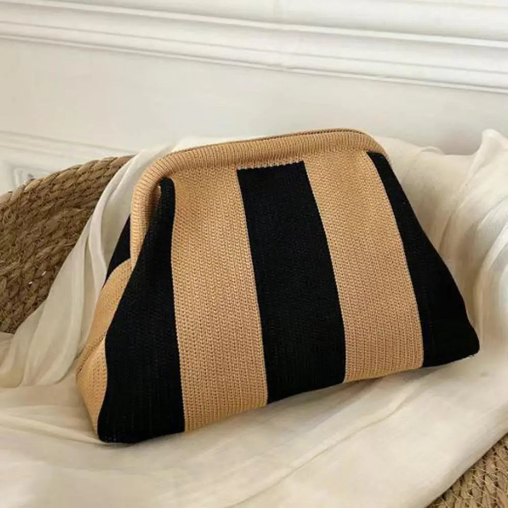 Pochette en crochet à rayures noires et beige, posée sur une surface blanche.
