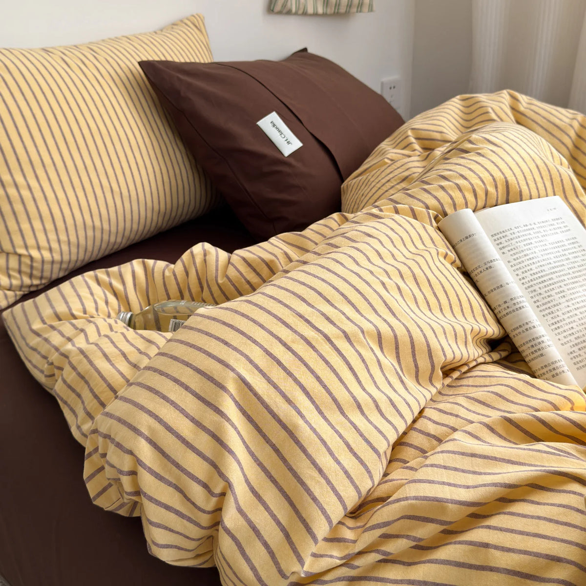 A yellow and brown striped duvet cover set with a matching pillow on a bed.
