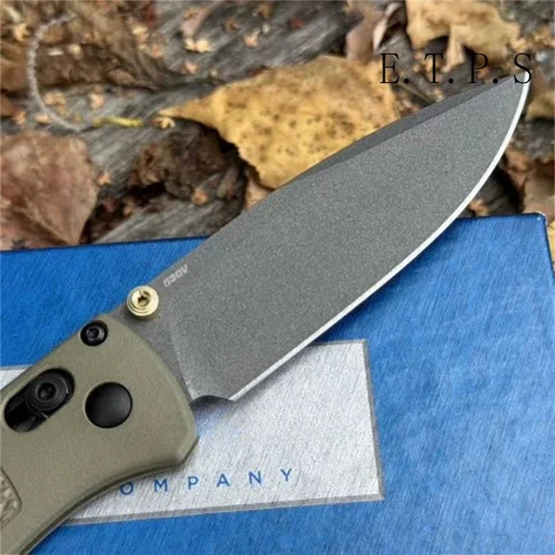 A gray CPM-20CV folding pocket knife with a drop point blade resting on a blue surface.