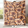A tan flannel throw blanket featuring a repeating pattern of cartoon capybara faces in brown and orange tones.