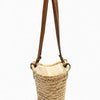 A handwoven straw tote bag with brown leather straps, shown against a white background.