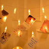 String lights with small photo clips hanging across a white wall