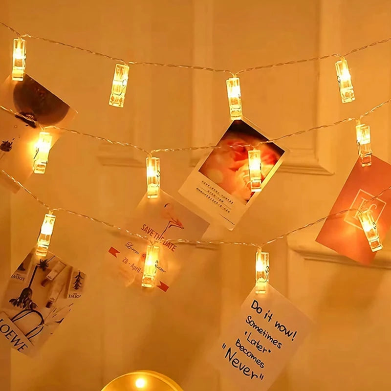 String lights with small photo clips hanging across a white wall