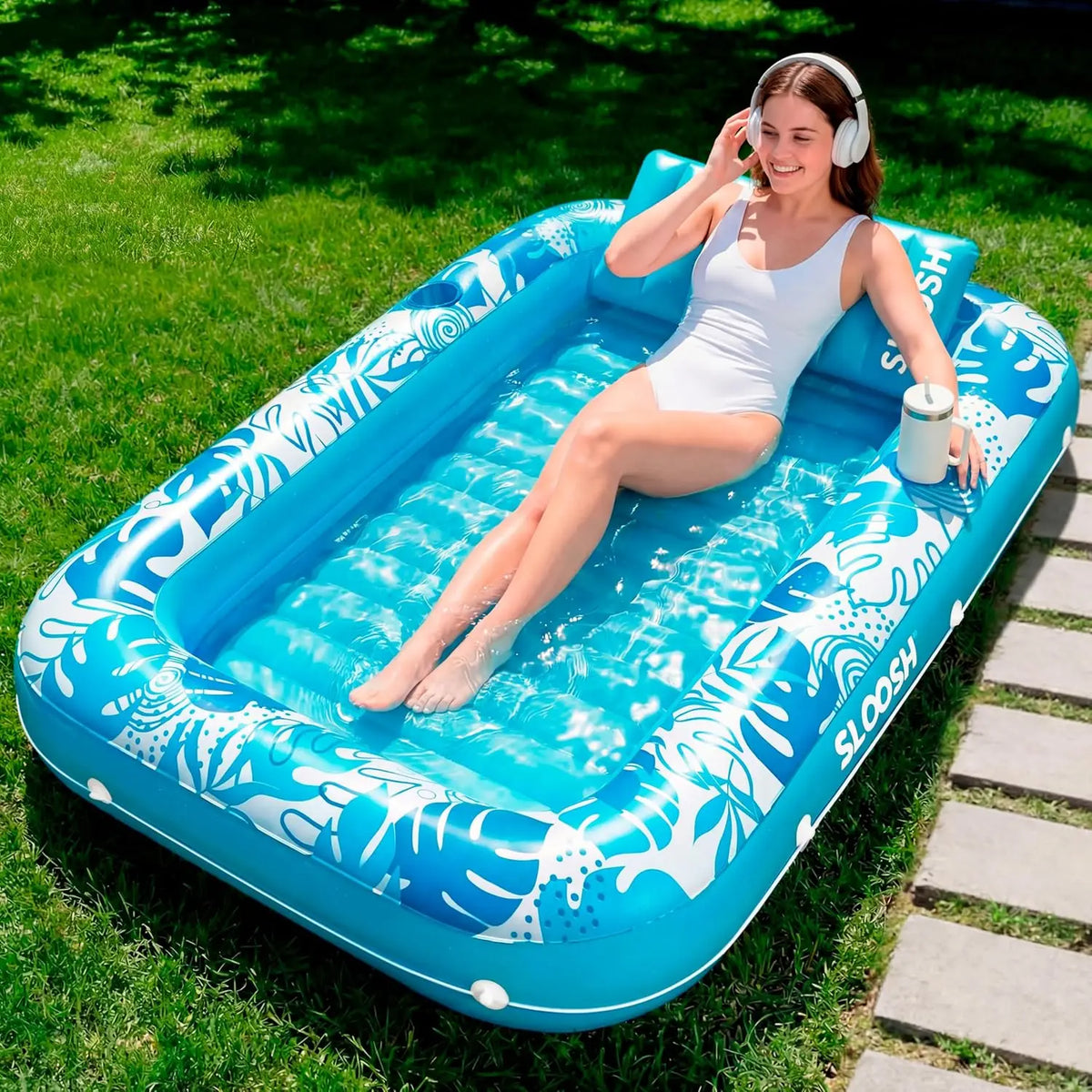 Eine Frau entspannt auf einem blauen aufblasbaren Poolschwimmring auf dem Gras.