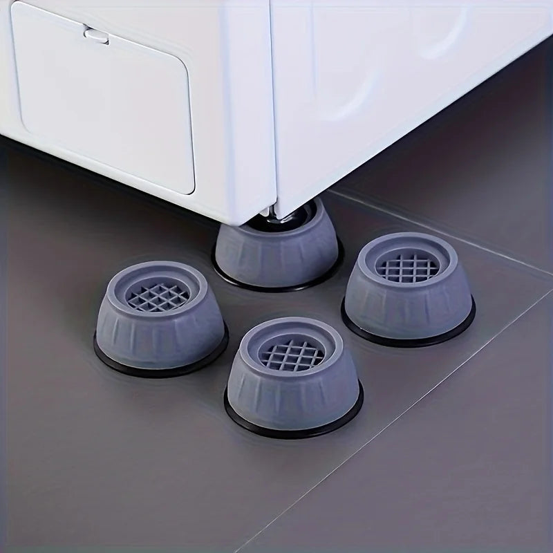 Three gray anti-vibration pads used as shock absorber feet for a white washing machine or dryer.