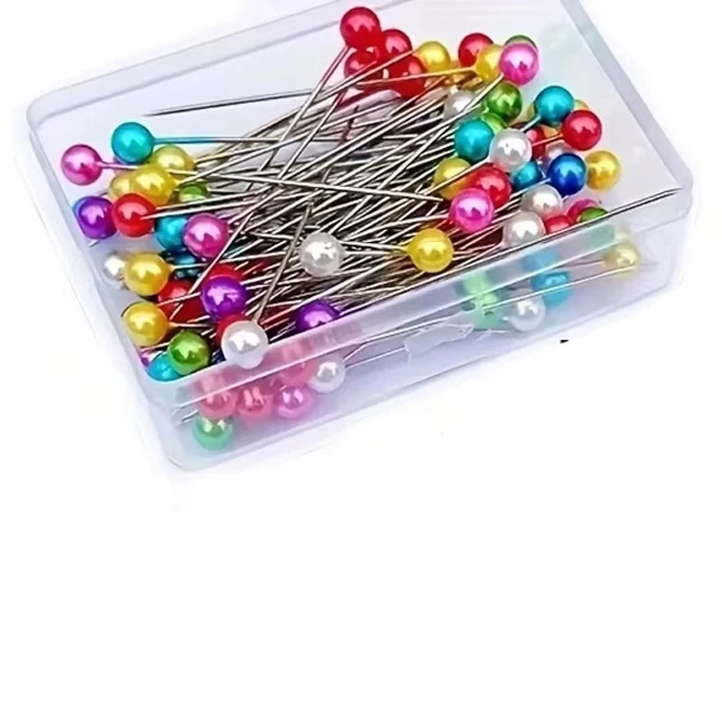 A collection of pearlized ball head sewing pins in various colors and shades stored in a clear plastic container.