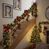 A wooden staircase decorated with an LED rattan Christmas garland and holiday accents.