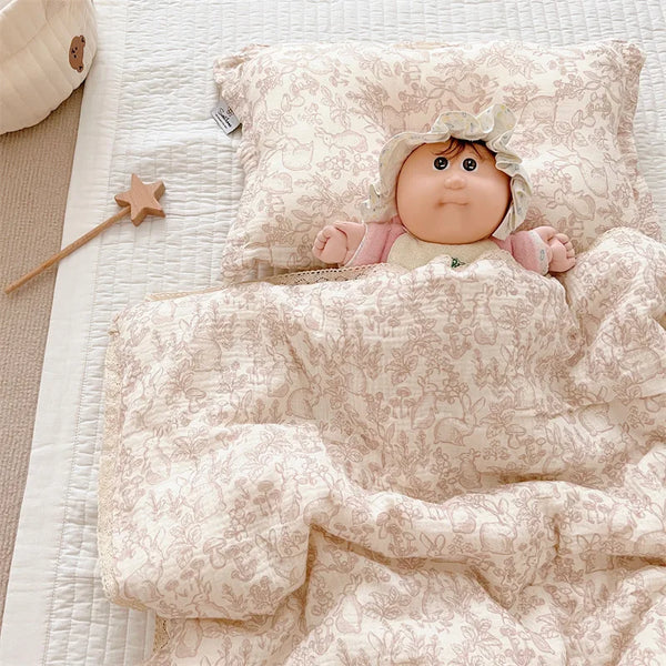 A vintage floral cotton muslin baby quilt featuring a baby doll wearing a bonnet.