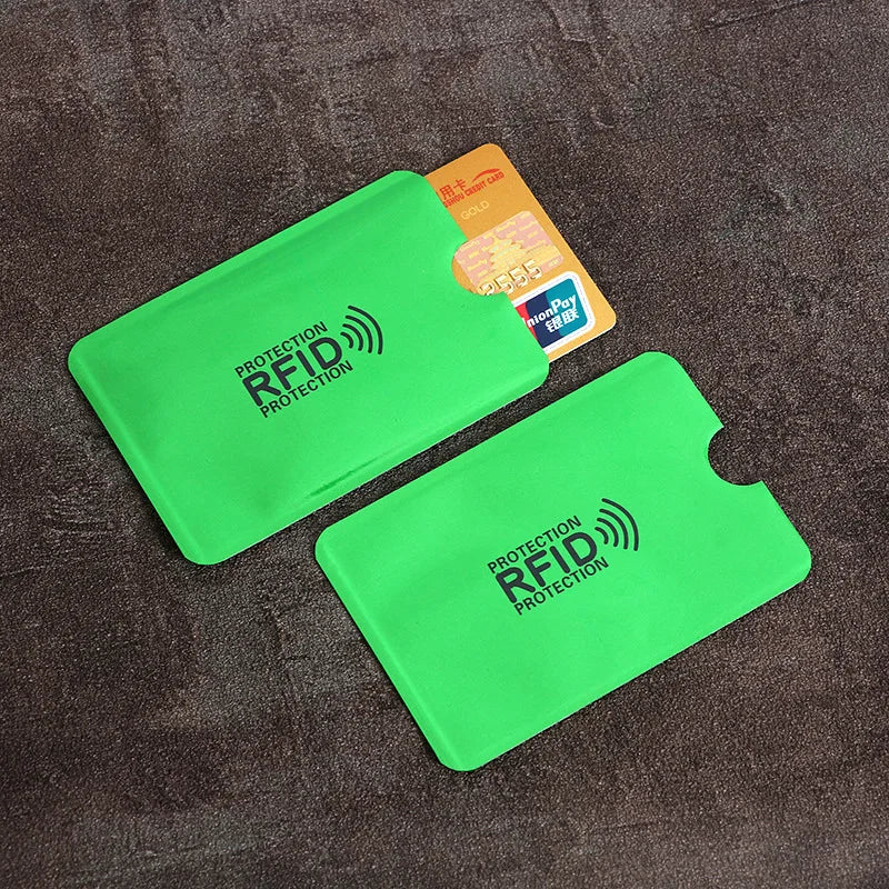 A bright green RFID protection card sleeve lying on a dark brown textured surface next to an orange identification card.