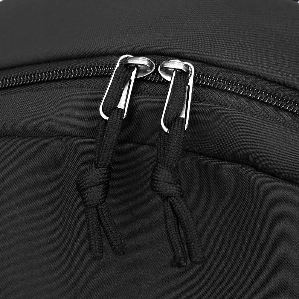 Close-up of a black canvas backpack featuring silver zipper pulls and black drawstrings.