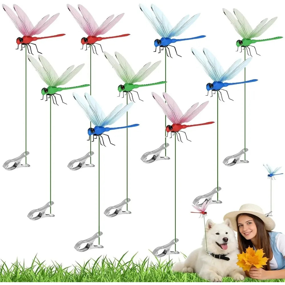 A collection of lifelike dragonfly garden decor clips in various colors hanging from a line against green grass.