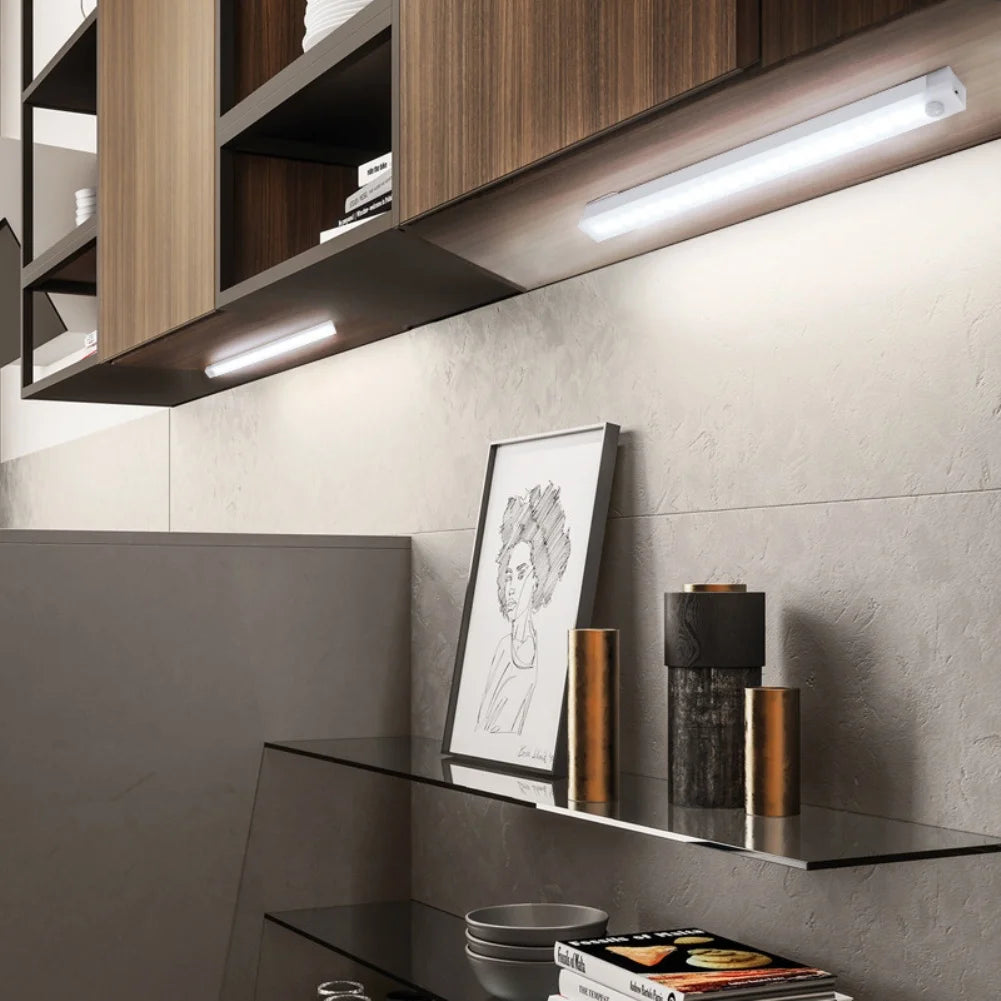 A modern kitchen cabinet with under-cabinet LED strip lighting illuminating a shelf display.