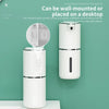 A white wall-mounted automatic soap dispenser is shown on a light green wall.