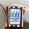 A canvas tote bag featuring a blue illustration of sardines in a rectangular frame on a striped background.