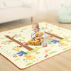 A baby is playing on a colorful soft foam play mat featuring woodland animals and trees.