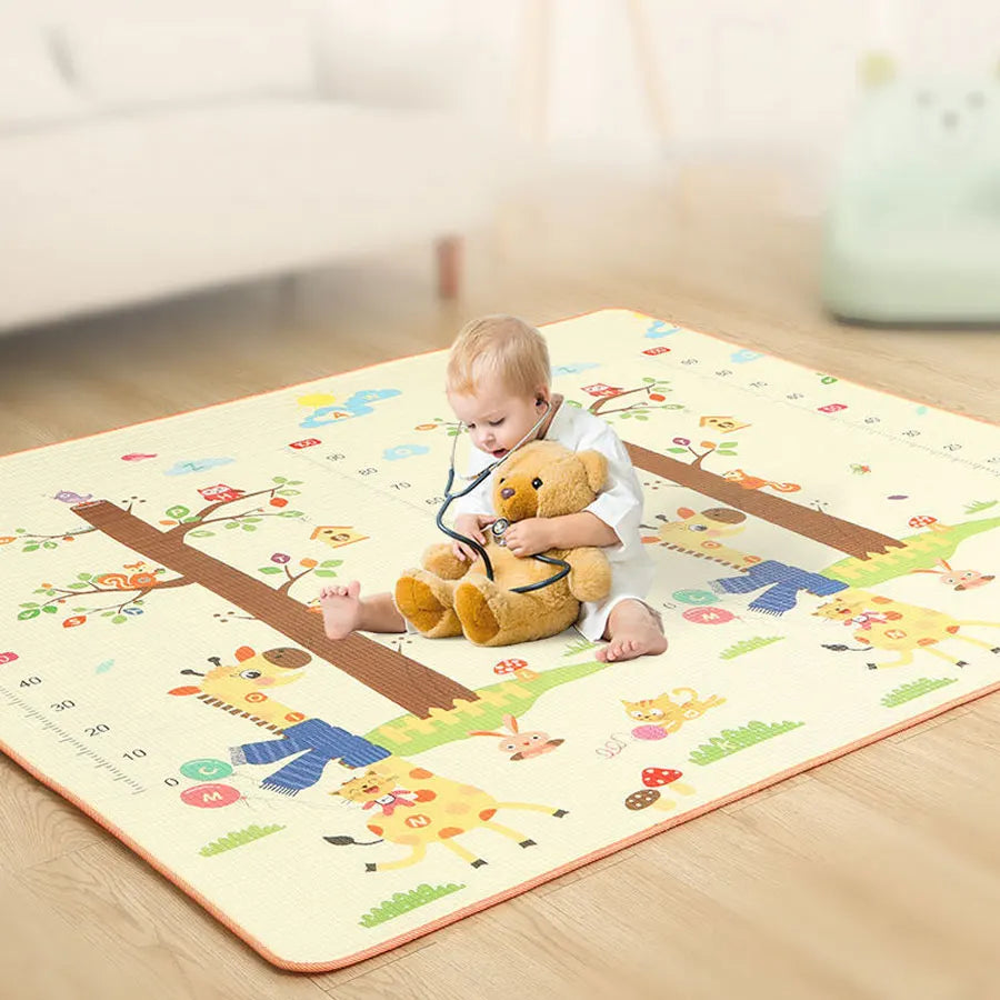 A baby is playing on a colorful soft foam play mat featuring woodland animals and trees.