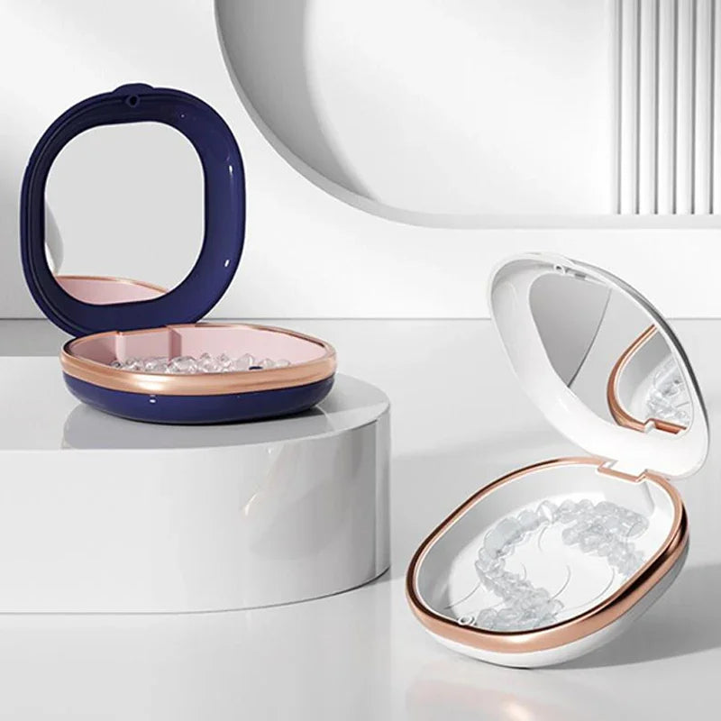 A compact orthodontic retainer case with a built-in mirror shown in purple and rose gold tones.