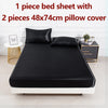 Schwarzes Satin-Bettwäscheset mit einer Bettdecke und zwei Kissenbezügen auf einem Bett.