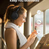 A woman wearing a gray knitted garment and headphones is smiling while using fitness equipment.