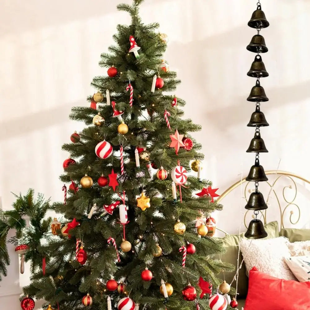 A decorated Christmas tree with ornaments and ribbons used as a backdrop for a vintage iron wind chime.