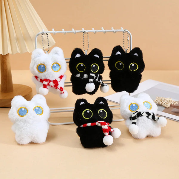Colección de llaveros de peluche de gatos negros colgando en un soporte de metal.