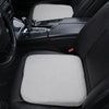 A close-up view of a gray ergonomic height-increasing car seat cushion placed in the back seat of a black car.