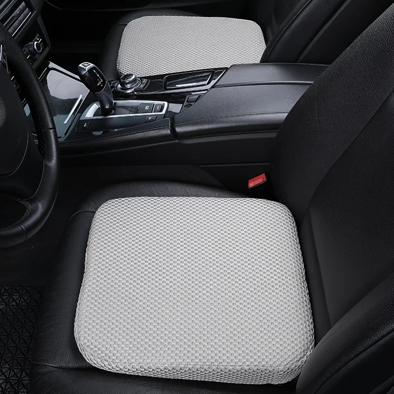 A close-up view of a gray ergonomic height-increasing car seat cushion placed in the back seat of a black car.