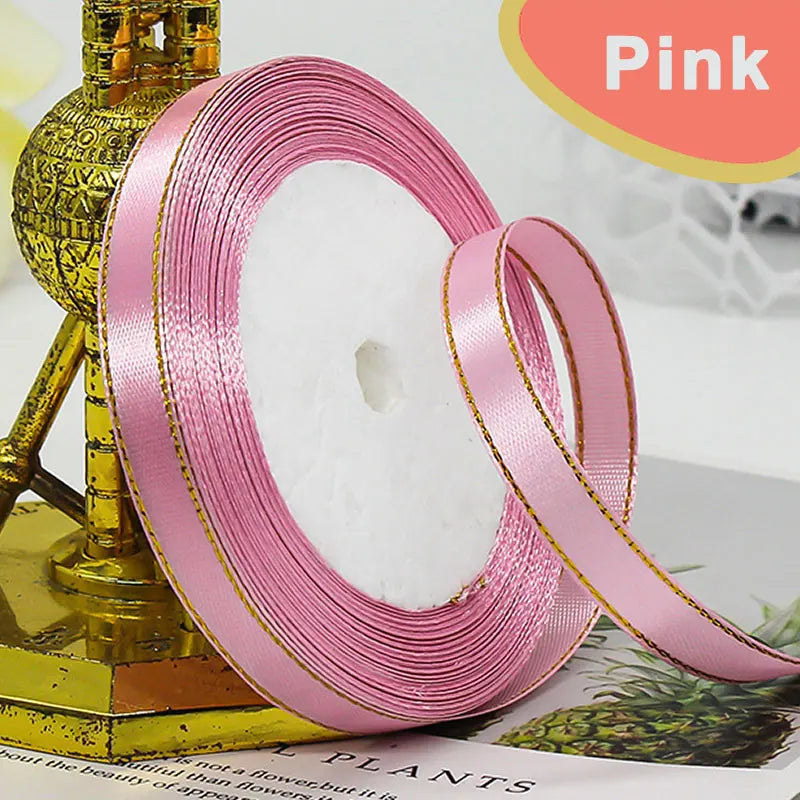 Pink gold-edge satin ribbon rolled on a stand for crafts and gift wrapping