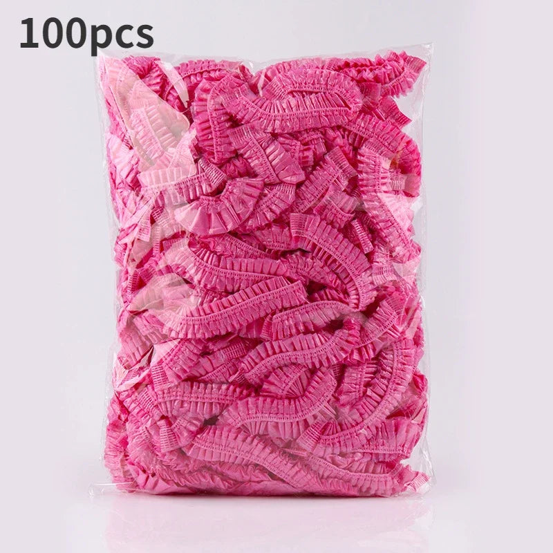 A package of 100 pink disposable transparent waterproof shower caps.