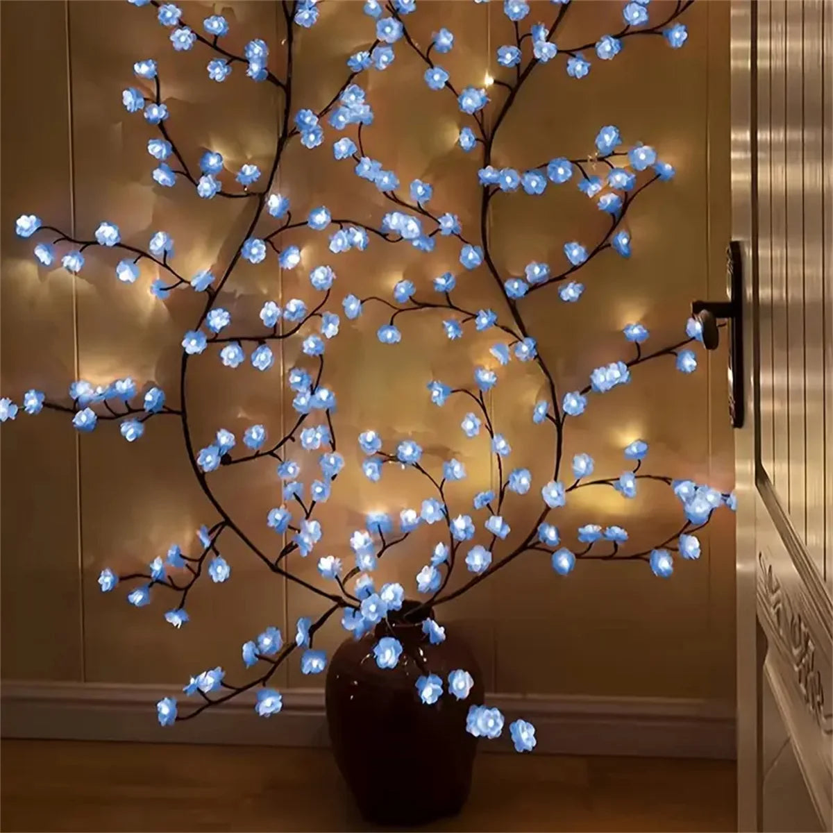 A decorative branch light featuring blue LED cherry blossoms displayed in a dark vase.