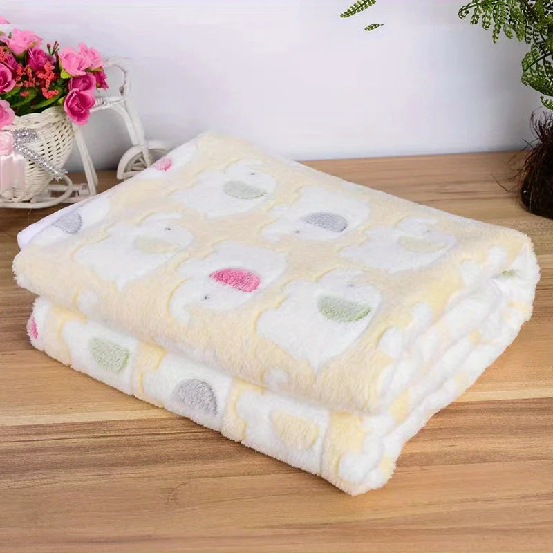 A stack of cozy flannel pet blankets featuring a cartoon elephant pattern in pastel colors on a wooden surface.