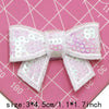 A set of five white and pink sequin bow patches for DIY crafts displayed on a pink grid background.