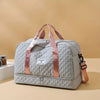 A light gray nylon travel duffle bag with pink straps resting on a beige surface.