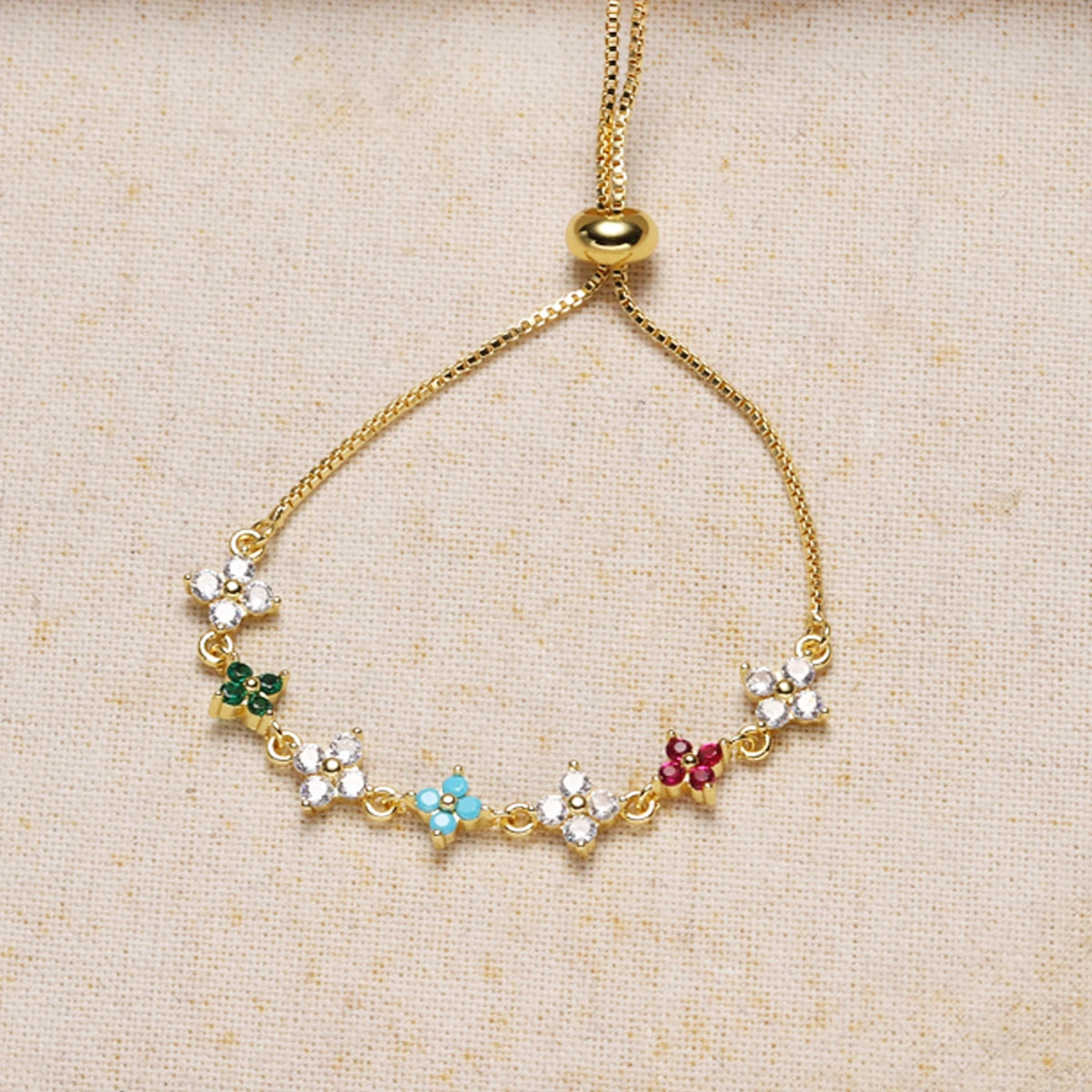 A delicate gold chain bracelet featuring small, colorful flowers and cubic zirconia stones.