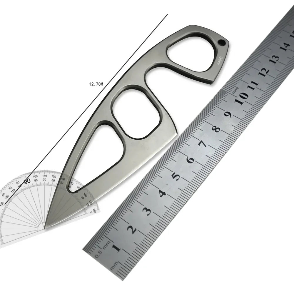 A fixed-blade neck knife with a serrated blade and a handle, shown next to a ruler.