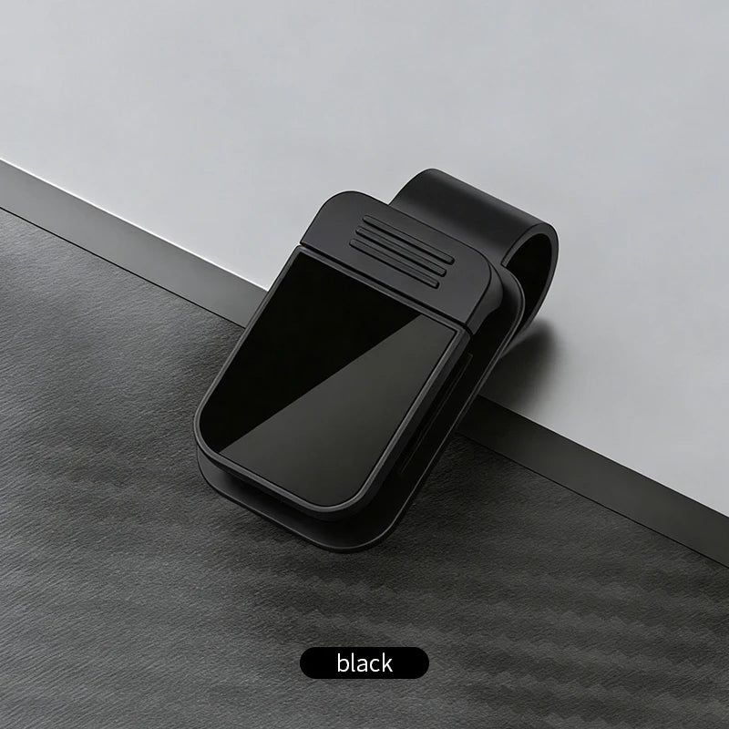 Schwarze Auto-Visor-Sonnenbrillen-Cliphalter auf dunkler grauem strukturiertem Untergrund.
