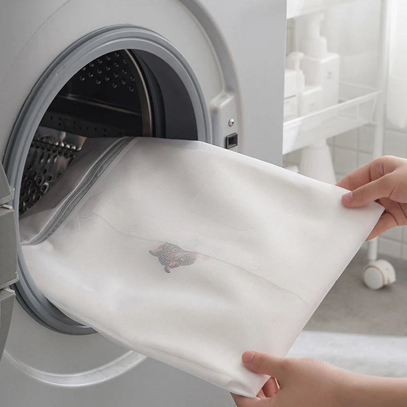 A white fine mesh laundry bag is being removed from a washing machine drum.