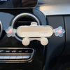 A crystal flower gravity car phone holder with auto-lock mounted on a black car interior panel.