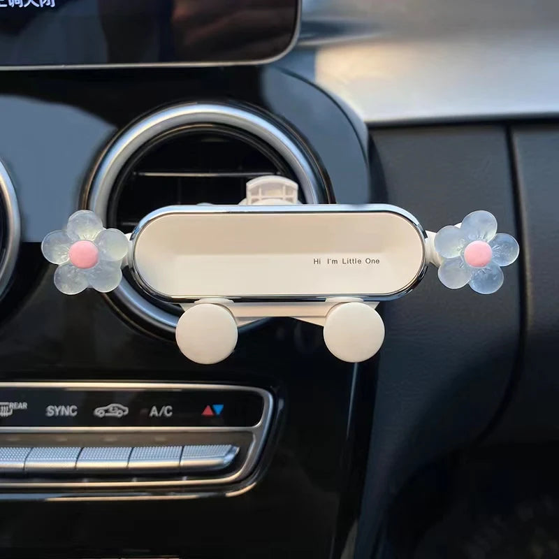 A crystal flower gravity car phone holder with auto-lock mounted on a black car interior panel.