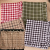 Three plaid fabric oven skirts in red, olive green, and brown tones with ruffled edges.