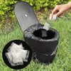 A black portable toilet with a lid is shown outdoors on grass, with hands dispensing absorbent powder into the bowl.