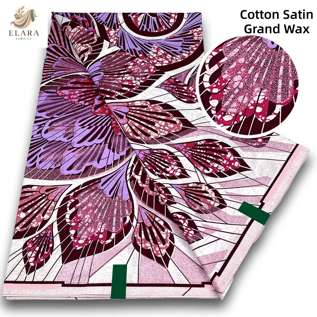 A roll of pink glitter African wax print fabric featuring purple and magenta floral patterns.