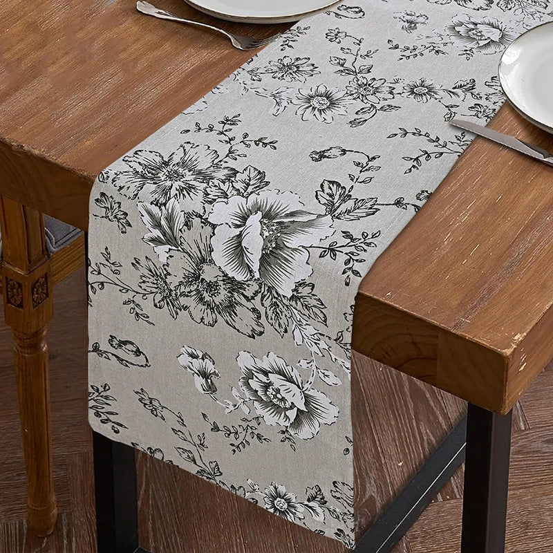 A beige floral patterned table runner displayed on a wooden table.