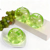 Green apple shaped squeeze toy and green grapes displayed on a white surface.