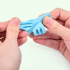 A hand holds a light blue ergonomic pencil grip trainer for posture correction.