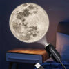 A glowing LED USB projector light displaying a full moon pattern illuminates a dark room.