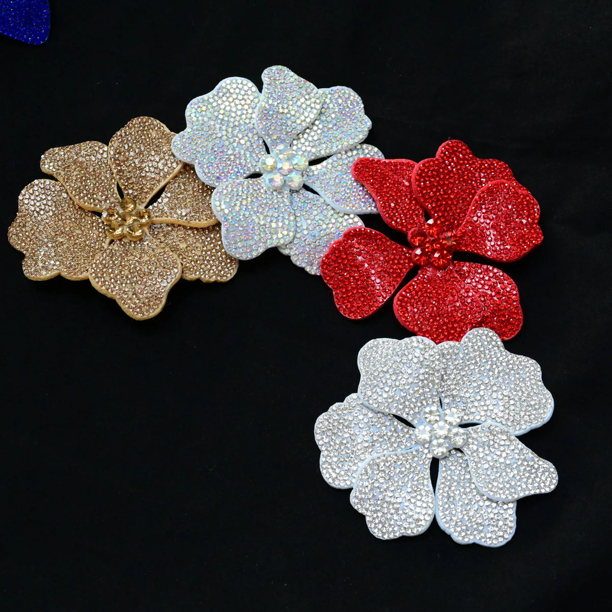 A set of three crystal rhinestone flower sew-on patches in gold, white, and red.