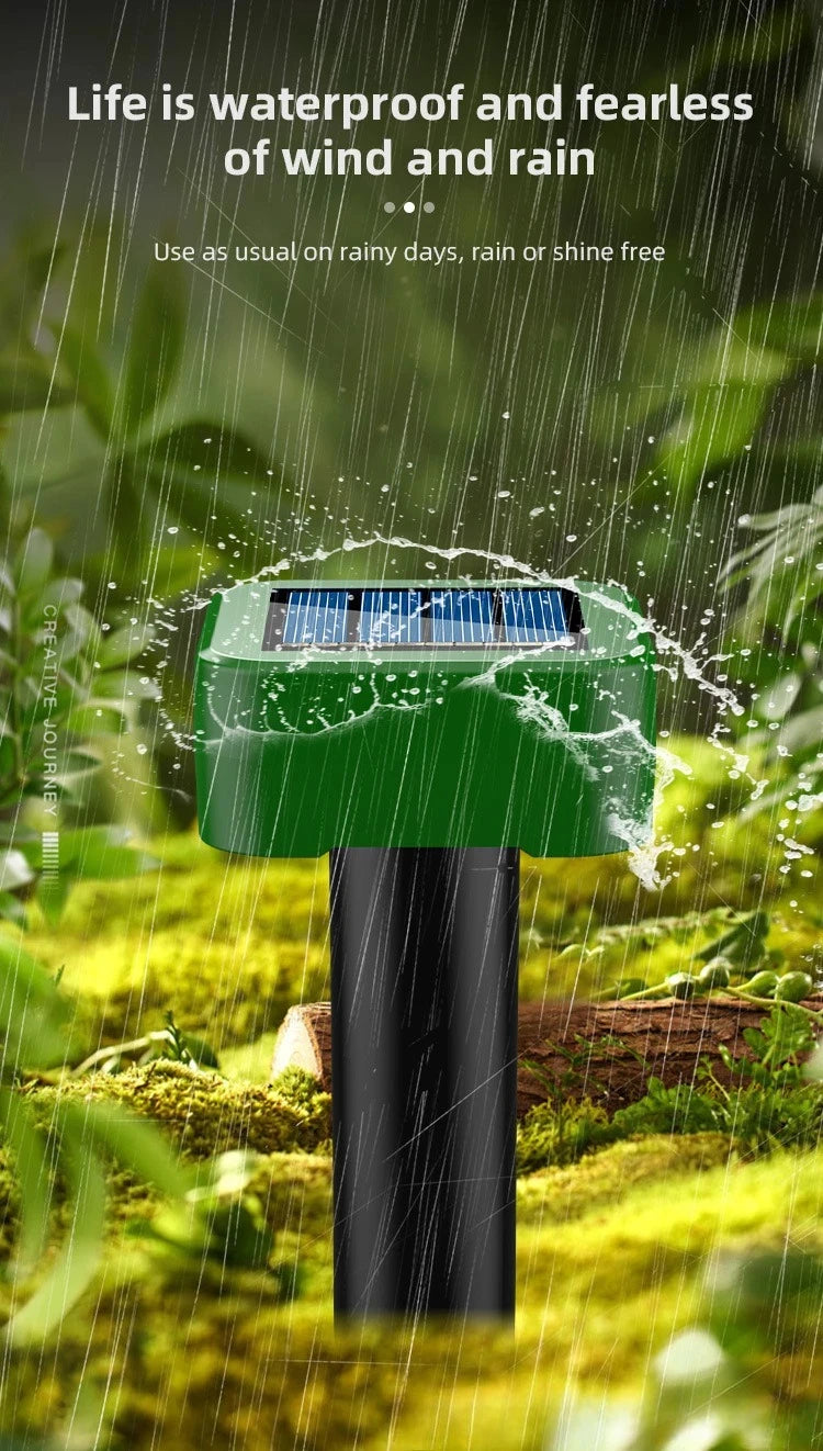 A green solar-powered ultrasonic animal repellent device is shown outdoors in a garden setting with rain falling.